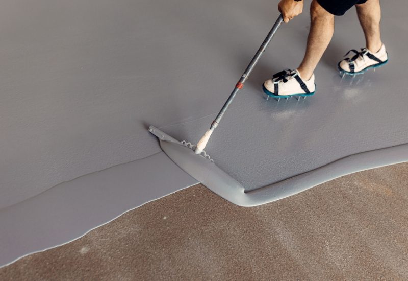 A,Construction,Worker,Applying,Grey,Epoxy,Resin,In,An,Industrial Epoxy flooring